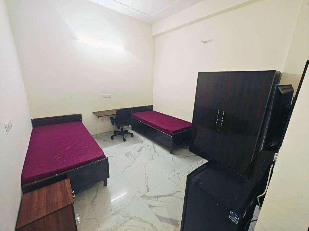 a room with two beds and a desk Girls PG in Sector 66